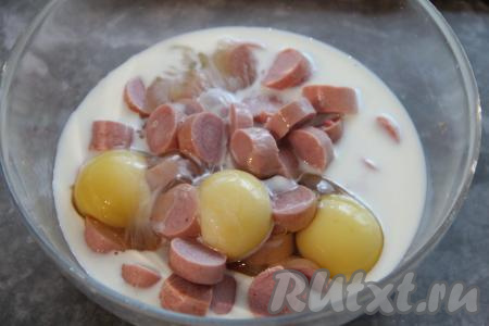 Влить молоко к сосискам и яйцам.