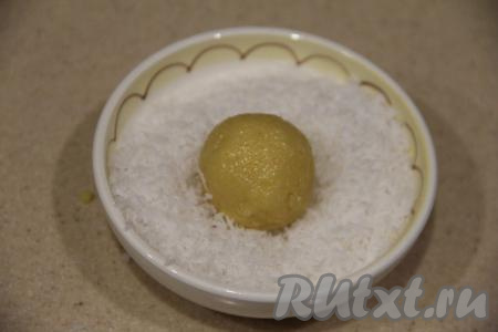 Защипнуть края лепёшки, подняв края кверху, и скатать шарик. Получится конфета с миндалём внутри. Обвалять конфетку со всех сторон в кокосовой стружке.