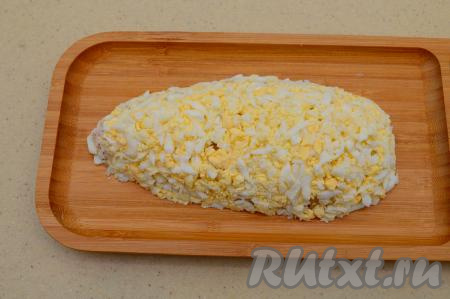 Куриные яйца заранее отварить вкрутую (в течение 9-10 минут с начала кипения воды), затем остудить их, очистить, натереть на крупной тёрке и покрыть ими равномерно бока и верх нашей будущей моркови. Слой яиц тоже немного присолить.