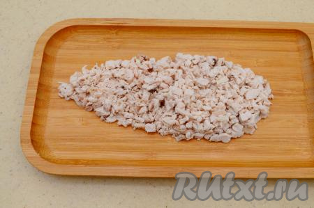 Заранее отварить куриное филе в подсоленной воде до готовности (на варку уходит обычно 25 минут с момента закипания), затем дать ему остыть, не вынимая из бульона (благодаря тому, что мясо будет остывать в бульоне, оно будет более сочным). Остывшее мясо нарезать на мелкие кубики и разместить на блюде для подачи в виде морковки. Вместо филе можно взять отварную колбасу, но мне больше нравится вариант с мясом. Чтобы салат не получился пресным, мясо надо сверху подсолить.