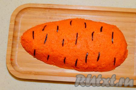 Для украшения салата острым ножом с маслин срезать тонко кожуру и нарезать её на тонкие полоски. Разложить полоски из маслин по поверхности салата, как бы имитируя бороздки на морковке.