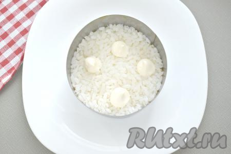 Прежде всего промываем рис водой, выкладываем в кастрюлю с достаточно большим количеством закипевшей подсоленной воды, ещё раз даём закипеть, перемешиваем и варим на небольшом огне до готовности риса (в течение 15-20 минут). Варёный рис откидываем на дуршлаг (или сито), промываем холодной водой и оставляем в дуршлаге (или сите), чтобы стекла лишняя вода и рис остыл. Морковь моем и отвариваем в кожуре до готовности (на это потребуется около 25-30 минут после закипания воды), затем, достав из воды, даём остыть и очищаем. Яйца варим 9-10 минут после начала кипения воды, затем остужаем их в ледяной воде и очищаем. Собирать слоёный салат "Мимоза" можно в глубоком салатнике, в порционных креманках или, как сделала я, используя сервировочное кольцо. Первым слоем салата выкладываем варёный рис, смазываем его майонезом.