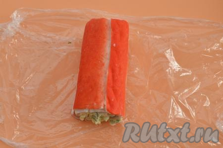 Сформированный рулет из крабовых палочек с начинкой из творожного сыра и яиц плотно завернуть в пищевую плёнку.