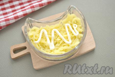 Вторым слоем выкладываем картофель, натёртый на крупной тёрке, немного солим, наносим майонез.