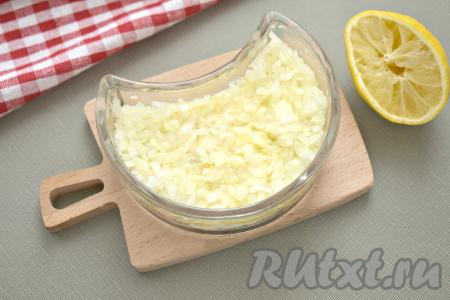 Очищаем лук, мелко нарезаем его, перекладываем в небольшую ёмкость, взбрызгиваем лимонным соком, перемешиваем и оставляем на пару минут. Лук отжимаем и выкладываем в салатник третьим слоем.
