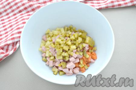 На кубики такого же размера нарезаем огурец. Складываем огурцы и сосиски в миску с морковкой и картофелем.