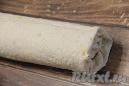 Подвернуть немного два боковых края лаваша на начинку и свернуть лаваш с начинкой в плотный рулет, начиная сворачивать от края с картошкой.