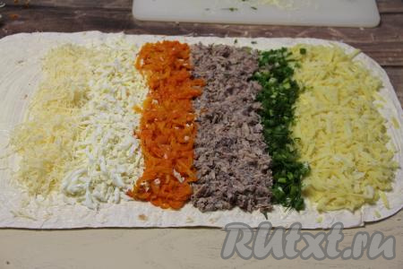 Отступив от краёв лаваша по 1 сантиметру, выложить полоску картофеля, натёртого на крупной тёрке, затем идёт небольшая полоска зелени. Далее выложить консервированную рыбку. Морковь натереть на крупной тёрке и выложить следующей полоской. Рядом с морковью расположить полоску яиц, натёртых на крупной тёрке. Следующей полоской будет натёртый сыр. Вот такая яркая "зебра" у нас получилась. После сырной полоски нужно оставить свободными 3 сантиметра лаваша, смазанного майонезом.