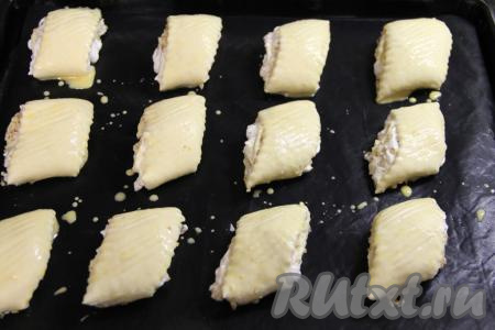 Переложить заготовки печенья на противень, застеленный ковриком для выпечки (или пергаментной бумагой). Верх печенюшек смазать взбитым желтком.