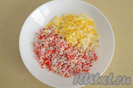 С крабовых палочек снять слюду, затем нарезать их достаточно мелко, переложить в глубокую тарелку, добавить яйцо, натёртое на крупной тёрке.