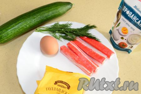 Подготовить продукты для приготовления рулетиков из огурца с крабовыми палочками и сыром. Крабовые палочки разморозить при комнатной температуре. Яйцо сварить вкрутую (в течение 9-10 минут после начала кипения воды), затем полностью остудить, залив холодной водой, и очистить. Огурец для этой закуски нужно брать длинный, достаточно плотный, желательно, без крупных семечек. Веточки укропа промыть водой, стряхнуть лишнюю воду.