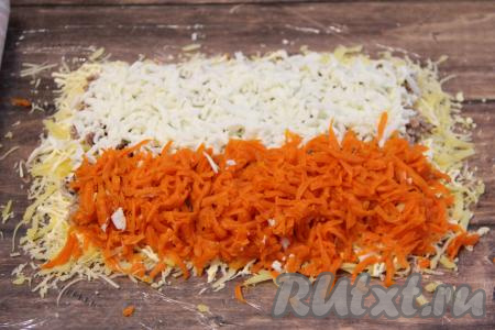 Яичные белки натереть на крупной тёрке. Очищенную морковку тоже натереть на крупной тёрке. Выложить белки и морковь двумя полосками поверх консервов.