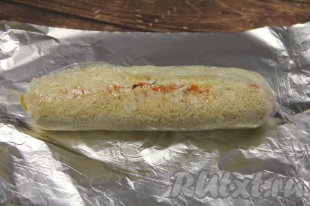 Начиная с широкой стороны прямоугольника и помогая себе пищевой плёнкой, свернуть салат "Мимоза" в плотный рулет. Завернуть рулет  в пищевую плёнку, концы плёнки прижать.