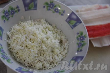 Очищенные яйца натереть на мелкой тёрке и переложить к крабовым палочкам.