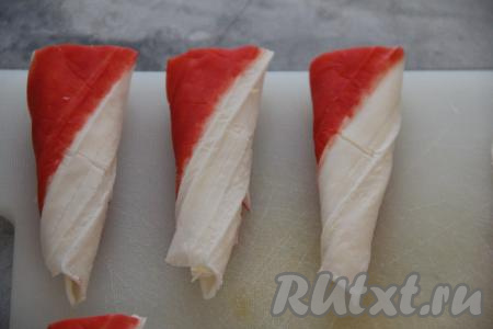 Завернуть в виде конуса сначала белую часть крабовой палочки, а затем - красную. Вот какие морковки получаются.