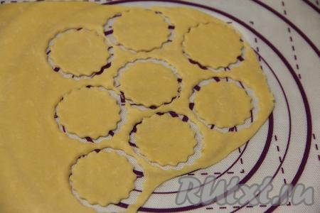 Тесто убрать в пакет и дать отдохнуть 30 минут при комнатной температуре. Затем на присыпанной мукой поверхности раскатать тесто скалкой в тонкий пласт. Вырезать кружочки диаметром 6 сантиметров. Я вырезала с помощью вырубки для печенья с рифлёным краем, можно воспользоваться подходящим по диаметру стаканом или кружкой.