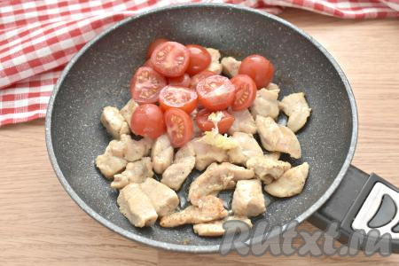 Добавляем к обжаренным кусочкам курицы пропущенный через пресс зубчик чеснока и нарезанные помидоры.