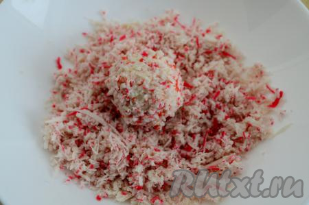 Каждый шарик обвалять со всех сторон в заранее отложенных натёртых крабовых палочках. Отправить в холодильник на 1 час, чтобы закуска стабилизировалась.