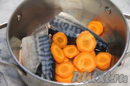 Скумбрию, если она заморожена, нужно разморозить, затем удалить у неё из брюшка внутренности и чёрную плёнку, отрезать хвост и голову. Тщательно промыть рыбку водой и разрезать на две части. Скумбрию, разрезанную пополам, выложить в кастрюлю, добавить очищенную морковь, нарезанную на тонкие кружочки.