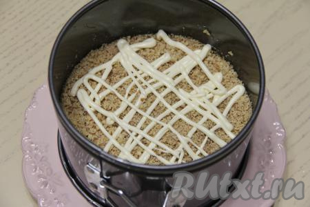 Грецкие орехи измельчить, распределить их поверх ветчины, покрыть сеточкой из майонеза.