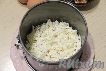 Этот салат нужно формировать слоями. Я формировала его с помощью металлического формовочного кольца диаметром 18 сантиметров, можно просто выложить слои в глубоком салатнике. Кольцо поставить на плоскую тарелку. Сырок натереть на тёрке и выложить первым слоем.