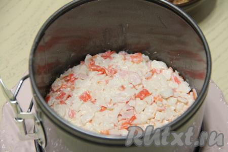 Поверх желтков выложить слой крабовой массы, разровнять и утрамбовать.