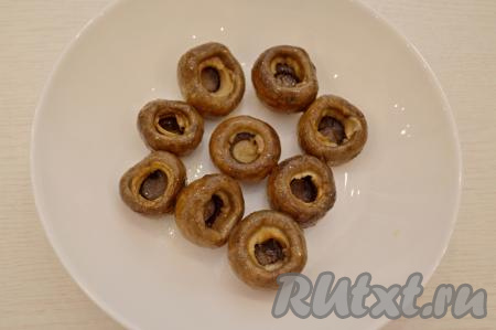 Взять маринованные шампиньоны. Я взяла шампиньоны, замаринованные в домашних условиях. От маринованных шампиньонов отделить ножки (ножки для этого рецепта нам не понадобятся). Грибочки лучше брать среднего размера с диаметром шляпки 2-4 сантиметра.