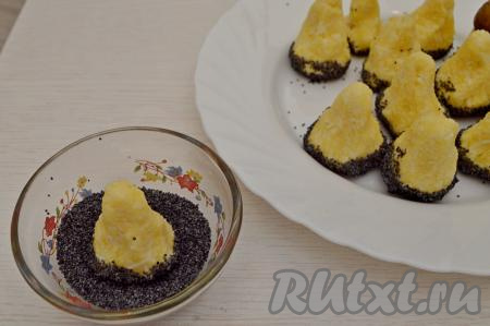 В отдельную мисочку насыпать мак (вместо мака можно взять чёрный кунжут). Влажными руками из массы сформировать конусообразную заготовку ножки гриба. Основание ножки должно быть плоским, чтобы грибочек в дальнейшем устойчиво стоял на тарелке. Основание ножки гриба обвалять в маке и поставить на блюдо для подачи. Таким же образом сформировать все заготовки.