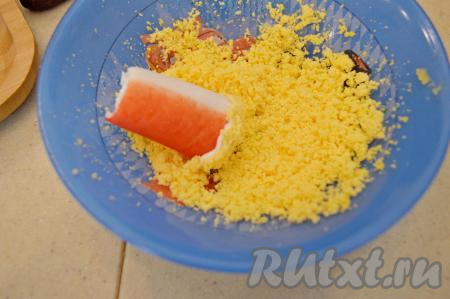 Окунуть этот же конец в раскрошенный желток. Затем другой конец половинки крабовой палочки окунуть в майонез, а после этого - в желток.