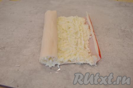 Аккуратно, начиная со стороны с начинкой, свернуть крабовую палочку в рулетик.