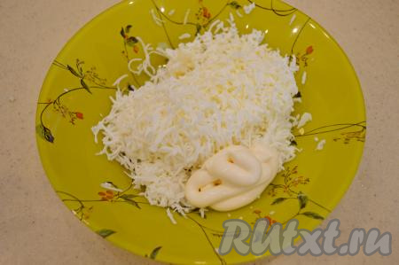 Из яиц вынуть желтки. Отложить желтки в сторону, они нам потребуются чуть позже для украшения. В миску с сыром натереть на мелкой тёрке яичные белки и зубчик чеснока, добавить столовую ложку майонеза.