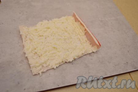 Крабовую палочку развернуть и равномерно смазать её примерно 1 столовой ложкой белково-сырной массы, оставив красный кончик палочки без начинки.