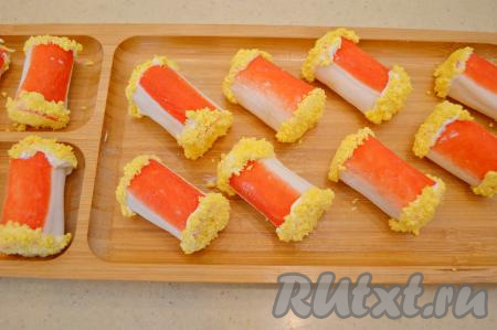 Подготовленную половину крабовой палочки выложить на блюдо для подачи. Аналогично оформить желтком все рулетики, выкладывая их на блюдо для подачи. Всего у меня получилось 12 рулетиков. Если вы готовите закуску заранее, тогда разрезать фаршированные крабовые палочки и оформлять их майонезом и желтком лучше непосредственно перед подачей, чтобы желток получился особенно аппетитным, "пушистым", благодаря этому закуска очень симпатично смотрится на столе.