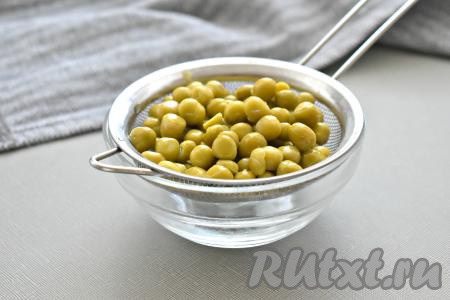 Зелёный консервированный горошек из банки перекладываем на сито (или на дуршлаг). Ждём, пока жидкость полностью сольётся.