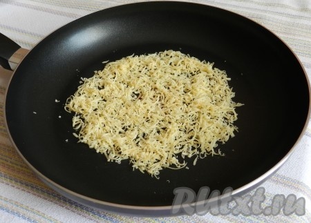 Сковороду разогреть, насыпать на нее небольшое количество натертого сыра тонким слоем.