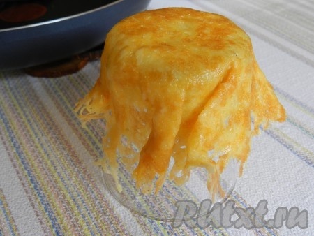 Через несколько секунд поддеть сыр лопаткой (расплавленный сыр легко снимается со сковороды), и быстро накрыть им дно перевернутого стаканчика, немного прижать руками, придав сырной корзинке форму. 