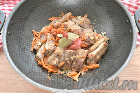 К рёбрышкам и овощам добавляем лавровые листья, томатную пасту (можно заменить на томатный соус или кетчуп), по вкусу солим, посыпаем молотыми специями.