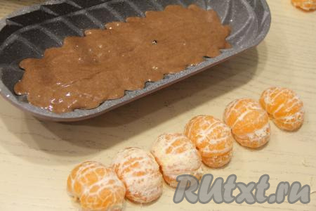 Мандарины заранее почистить и разделить на половинки. В форму вложить половину теста. Я выпекала в литой форме размером 32х14 сантиметров и предварительно её не смазывала маслом, но тут всё зависит от качества формы.