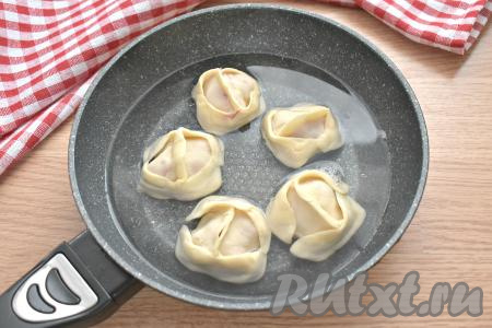 Манты заливаем горячей кипячёной водой так, чтобы она покрывала их до середины. Сковороду накрываем крышкой. На среднем огне доводим воду до кипения. Затем огонь убавляем до минимума и готовим манты 25 минут. В середине приготовления, при необходимости, можно добавить ещё воду, если она сильно выкипит.