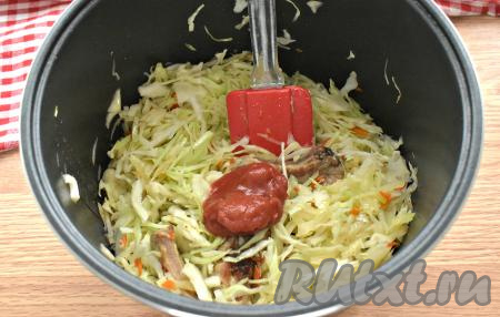 Через 10 минут после того, как мы добавили к рёбрышкам капусту, выкладываем к ней томатную пасту, перемешиваем. Мультиварку опять закрываем и продолжаем тушить оставшиеся 40 минут. За это время капусту с мясом нужно 2-3 раза перемешать.