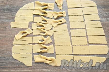 А теперь формируем хворост. Берём за один конец полоски и выворачиваем её через надрез. Подобным образом формируем весь хворост, не забывая раскатать оставшееся тесто. Рекомендую сразу сделать все заготовки хвороста, ведь во время жарки заниматься этим будет просто некогда - хворост готовится очень быстро, нужно быть внимательным, чтобы он не подгорел.