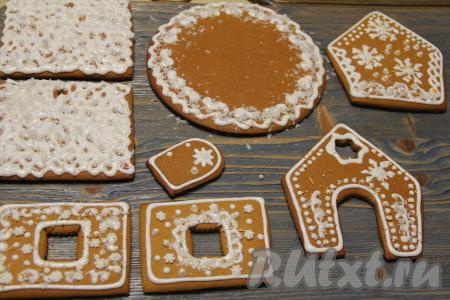 Я не особо умею рисовать, но крышу разукрасила глазурью и сразу посыпала её кокосовой стружкой, имитируя снег. Тоже сделала с подставкой. Ну а остальные детали украсила завитками и капельками. Оставить детали на 10 часов при комнатной температуре (до полного застывания глазури). Получившейся глазури хватило для росписи деталей двух домиков.