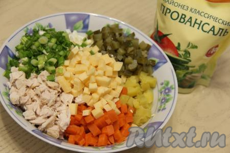 Зелёный лук и огурчики выложить в миску, подсолить салат по вкусу (учитывая солёность огурцов и сыра), перемешать салат. Заправить "Оливье" майонезом непосредственно перед подачей.