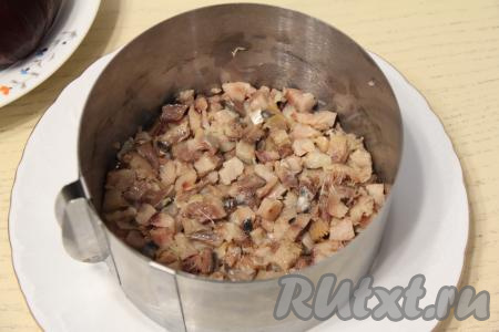 Копчёную скумбрию почистить, снимая кожу и отделяя филе от костей. Филе мелко нарезать (или порвать на волокна). Этот салат можно выкладывать слоями в глубоком салатнике или использовать сервировочное кольцо. Я взяла плоскую тарелку, поставила на неё металлические бортики для формирования салата диаметром 20 сантиметров. Первым слоем выложить копчёную скумбрию.