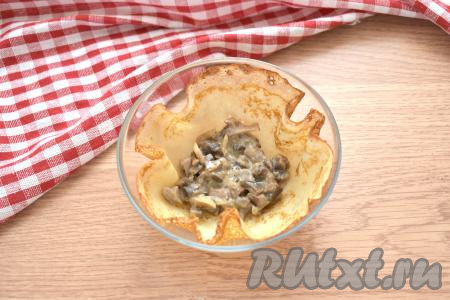 Чтобы нам было удобно собрать блины с грибным жульеном, возьмём небольшую пиалу. Помещаем в неё блин, выкладываем 1 полную столовую ложку тёплого жульена из грибов.