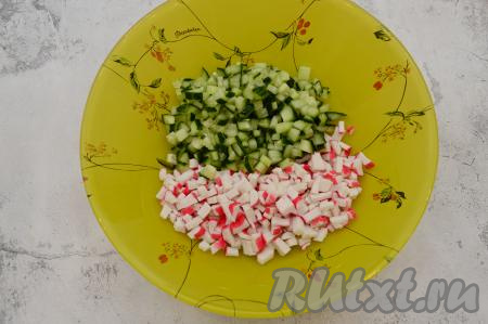 Огурчик и крабовые палочки нарезать на небольшие кубики, примерно, одинакового размера, переложить в глубокий салатник.