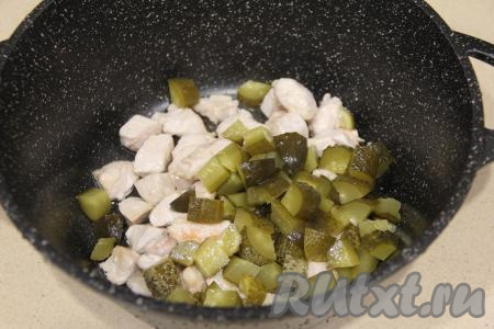 В кастрюлю переложить обжаренное куриное мясо, добавить огурцы, нарезанные на крупные кубики (или кружочки).