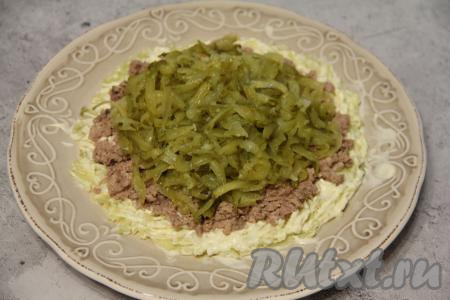 Огурцы натереть на крупной тёрке, затем отжать лишнюю влагу и выложить поверх печени, нарисовать сеточку из майонеза.