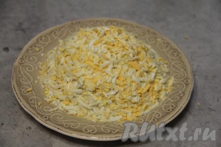 Натереть яблоко, очищенное от кожуры, на крупной тёрке, убирая косточки. Равномерно разложить натёртое яблоко поверх огурцов, нанести сеточку из майонеза. Яйца натереть на крупной тёрке. Натёртыми яйцами покрыть салат сверху и по бокам, формируя пирамиду.