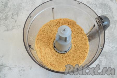 Измельчить печенье до состояния крошки. Если нет измельчителя, можно переложить печенье в целлофановый пакет, завязать его и поверх пакета прокатать скалкой, измельчая печенье в мелкую крошку.